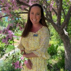 Woman in yellow dress smiling under cherry blossom tree
