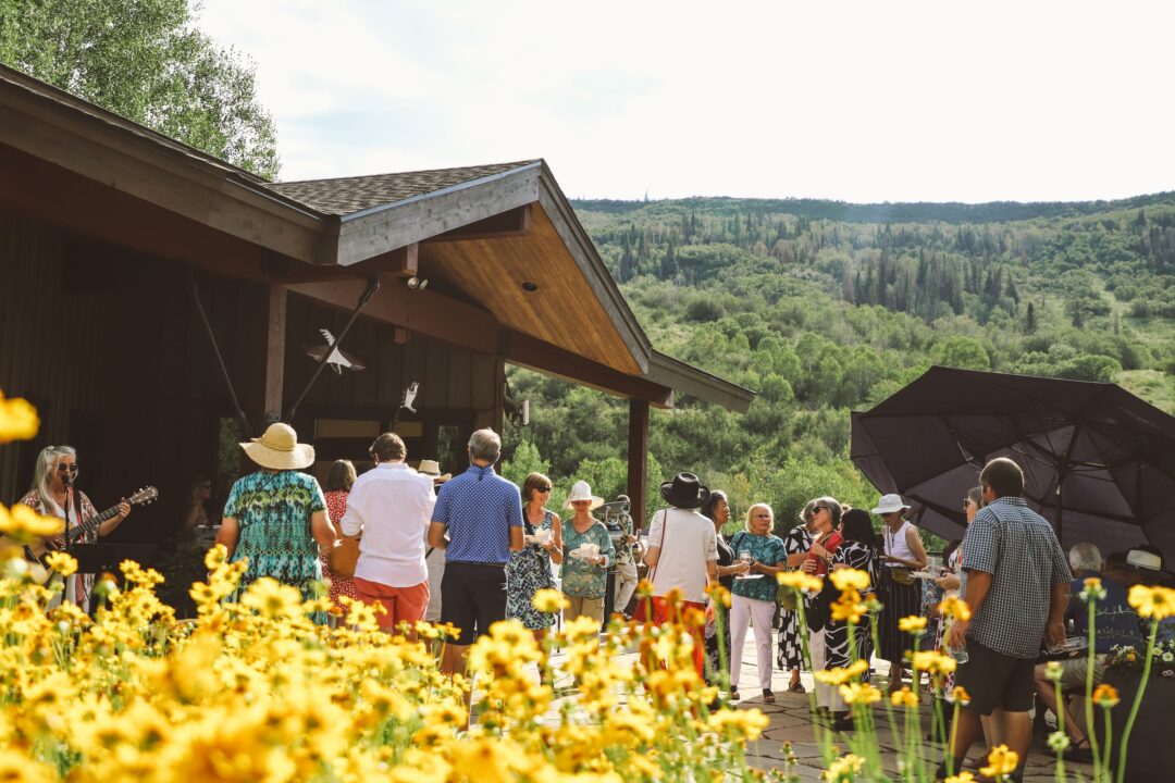 Yellow flowers beside a building and people drinking wine