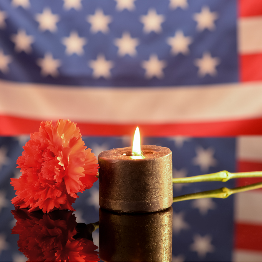burning candle and flower in front of an American flag