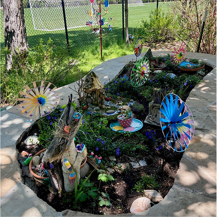 A small decorative garden with tiny fairy themed structures