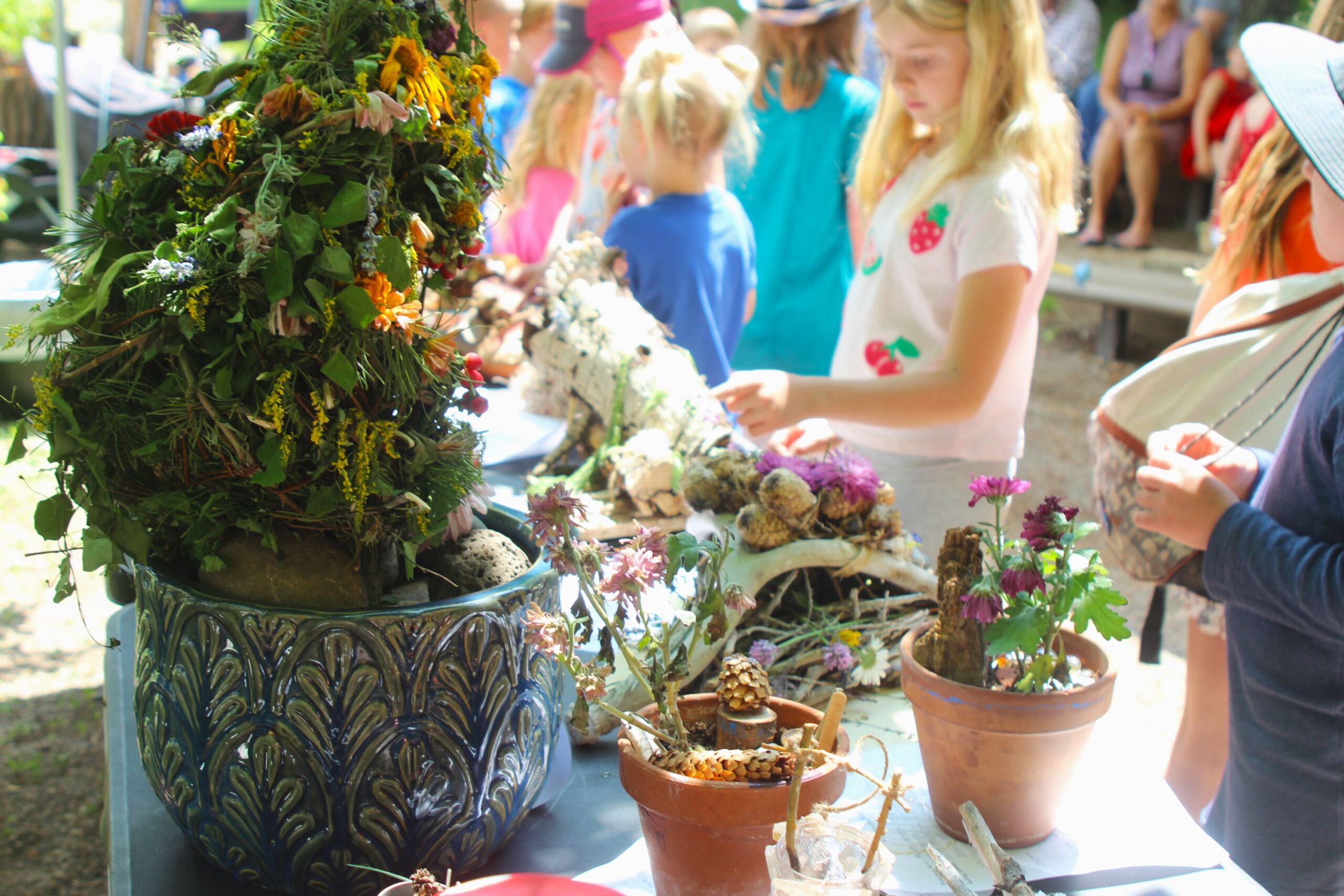 Children looking at a table of homemade fairy houses