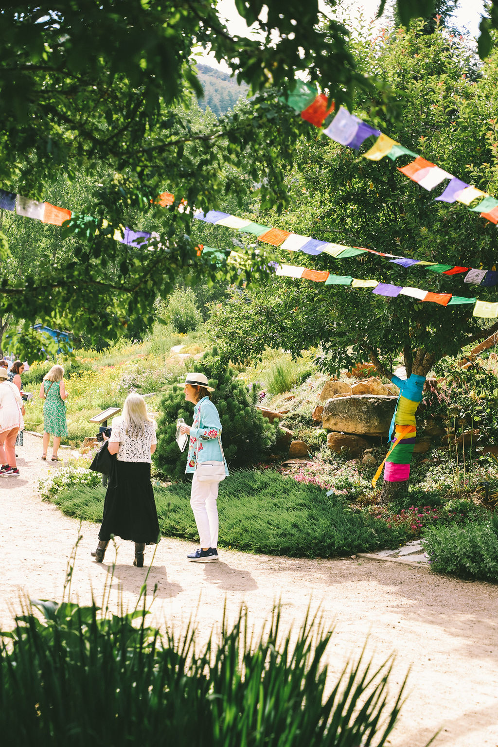 People walking beneath prayer flags in a garden