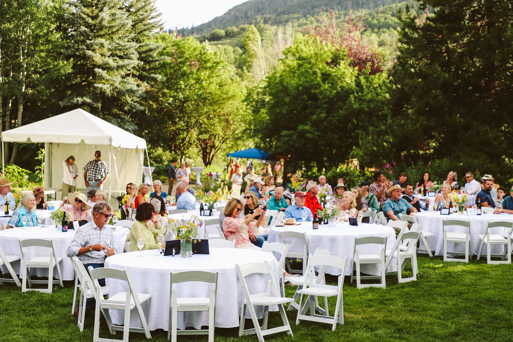 Guests seated at white tables on a lawn