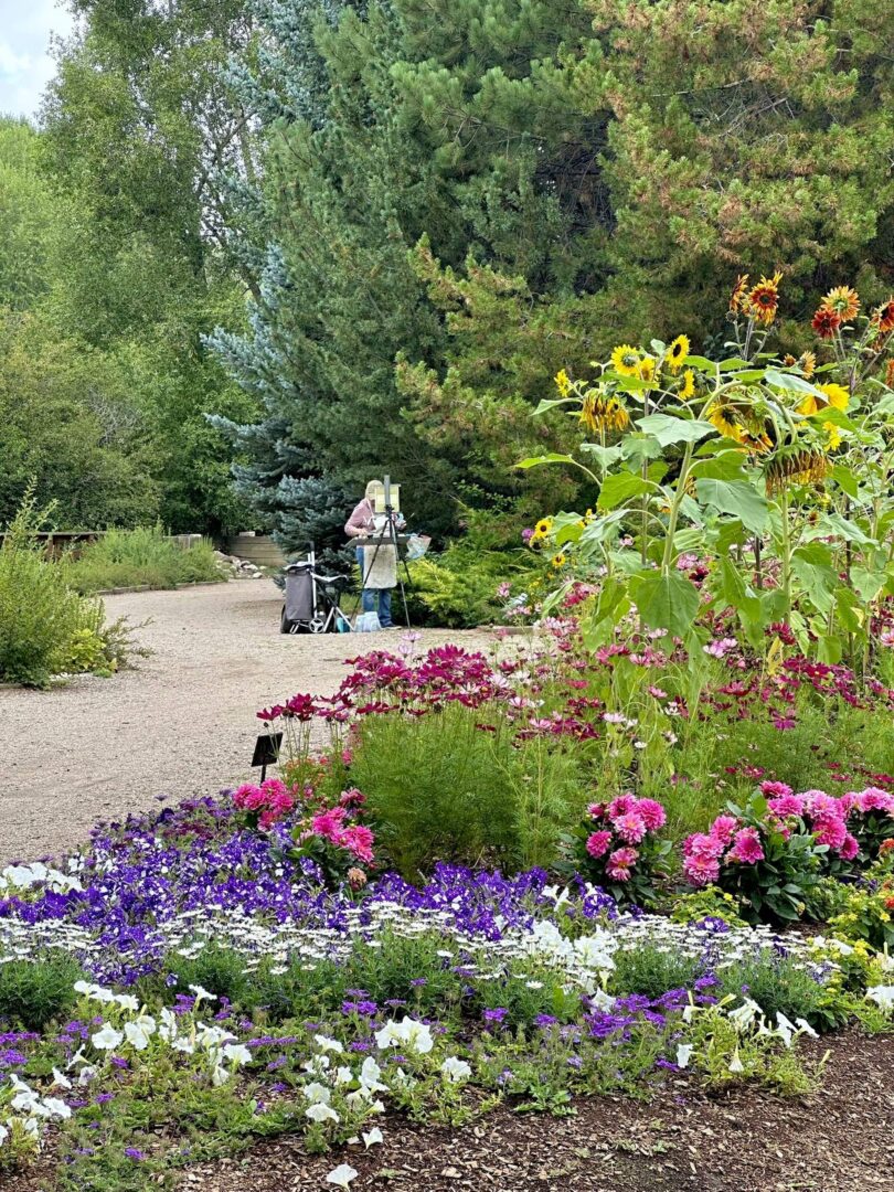 Plein Air painter painting by colorful flowers on a path