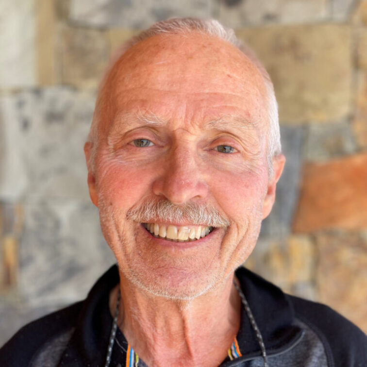 A man with a grey mustache smiling