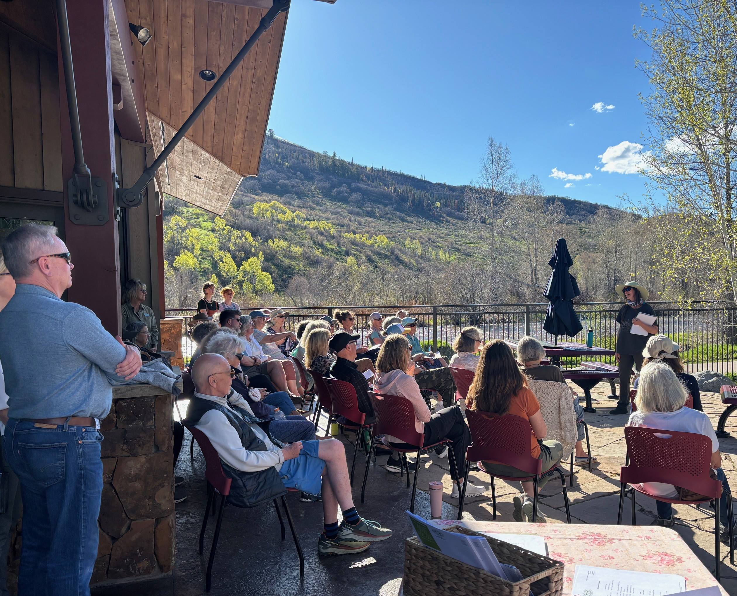 Volunteers gathered on the Trillium House patio listening to a staff speaker